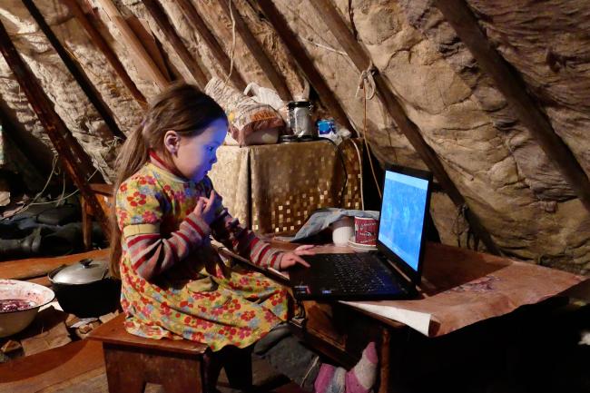 Petite fille nenetse dans une yourte devant un ordinateur